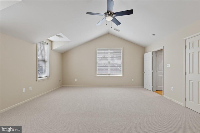 unfurnished bedroom featuring visible vents, light colored carpet, lofted ceiling, and multiple windows