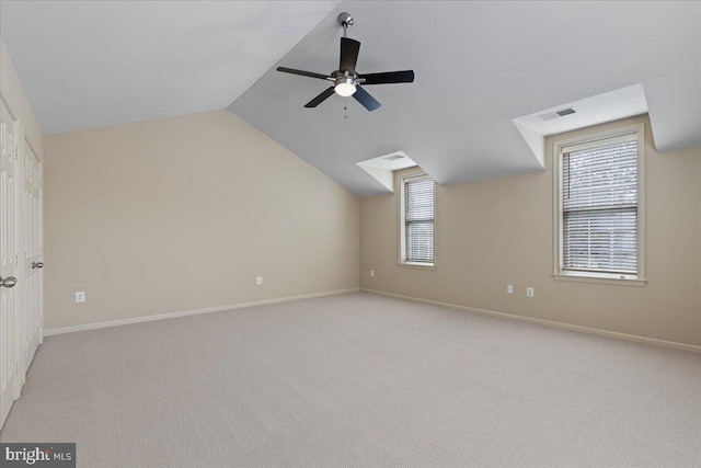 unfurnished room with visible vents, light carpet, plenty of natural light, lofted ceiling, and ceiling fan