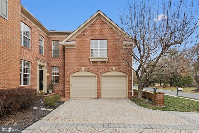 view of front of property featuring decorative driveway, an attached garage, and brick siding