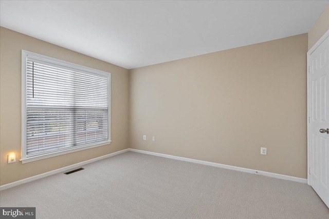 carpeted empty room featuring visible vents and baseboards