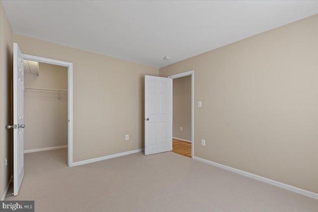 unfurnished bedroom featuring baseboards, carpet floors, a closet, and a spacious closet