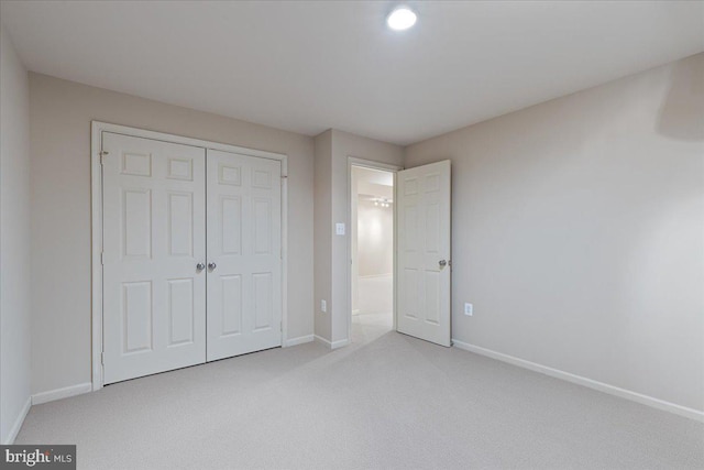 unfurnished bedroom featuring baseboards, a closet, and light carpet