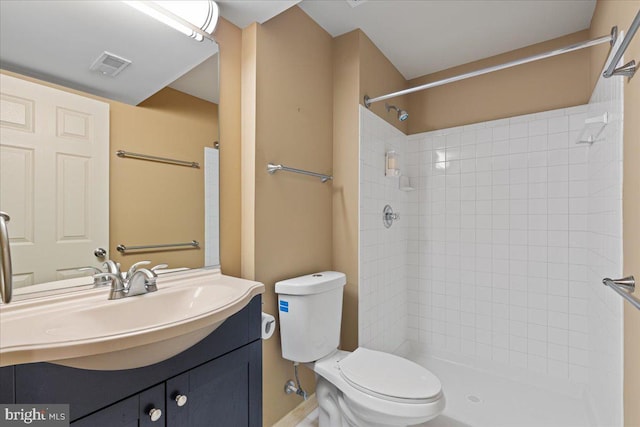 bathroom with a tile shower, visible vents, toilet, and vanity