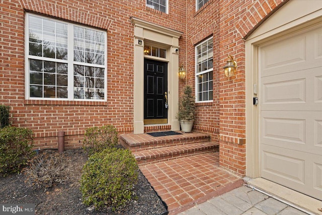 entrance to property featuring brick siding and an attached garage