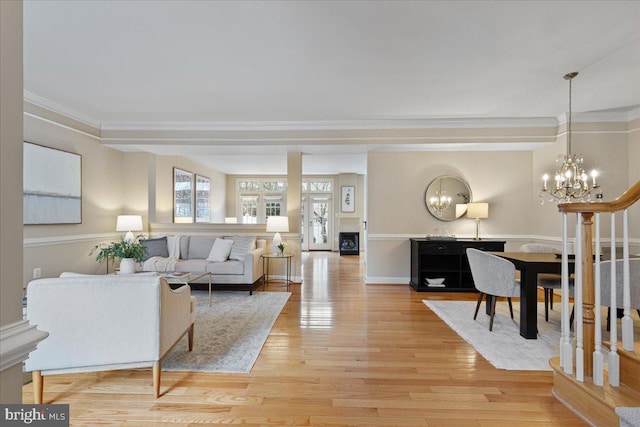 living area with a chandelier, crown molding, and light wood finished floors