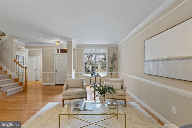 living area with baseboards, wood finished floors, stairs, and crown molding