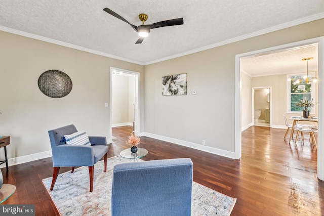 living area featuring ceiling fan with notable chandelier, a textured ceiling, dark hardwood / wood-style flooring, and ornamental molding