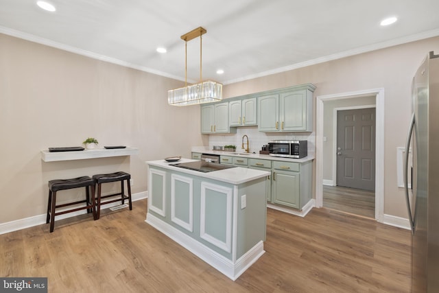 kitchen with a kitchen island, light hardwood / wood-style floors, backsplash, appliances with stainless steel finishes, and pendant lighting