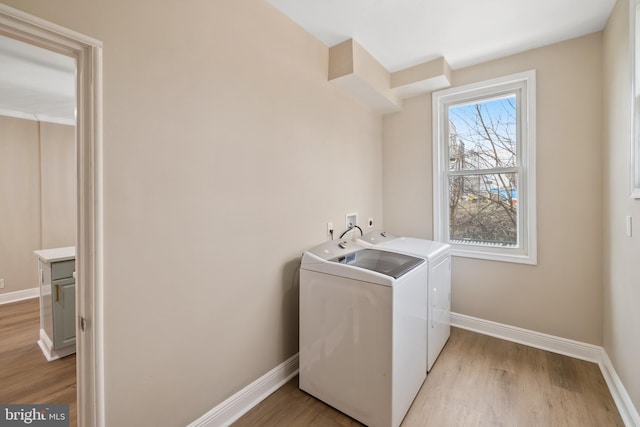 washroom with washing machine and clothes dryer and light hardwood / wood-style floors