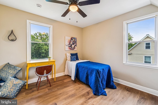 bedroom with multiple windows, ceiling fan, and wood-type flooring