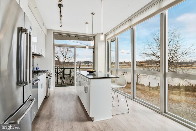 kitchen featuring dark countertops, freestanding refrigerator, light wood-type flooring, white cabinetry, and floor to ceiling windows