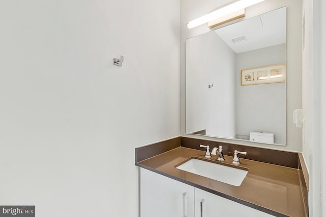 bathroom featuring toilet, vanity, and visible vents