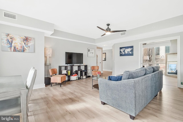 living area featuring baseboards, visible vents, ceiling fan, and light wood finished floors