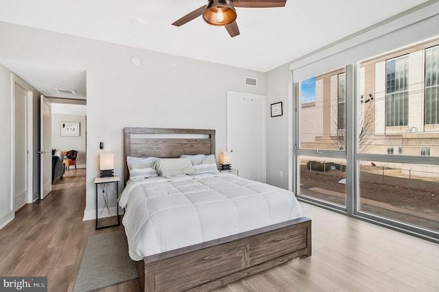 bedroom featuring ceiling fan, access to outside, wood finished floors, and visible vents