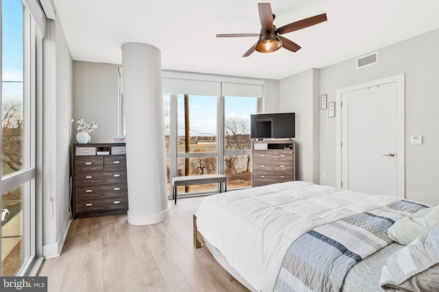 bedroom featuring light wood-style flooring, a ceiling fan, baseboards, visible vents, and floor to ceiling windows