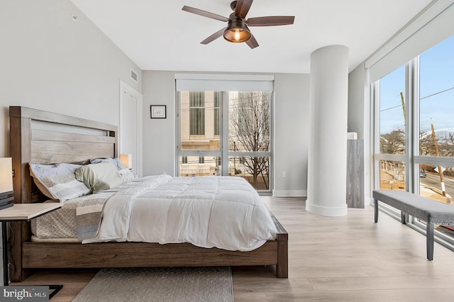 bedroom with visible vents, multiple windows, a wall of windows, and light wood-style flooring