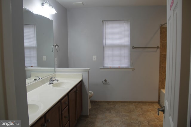 bathroom with toilet, double vanity, and a sink