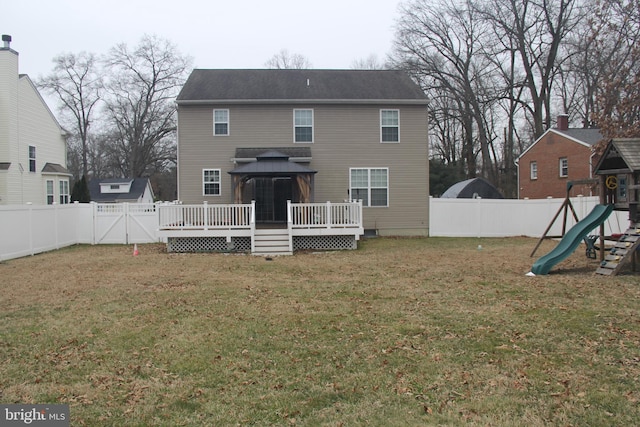 back of property with a lawn, a fenced backyard, a gazebo, a wooden deck, and a playground