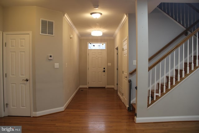 foyer featuring crown molding, visible vents, wood finished floors, baseboards, and stairs