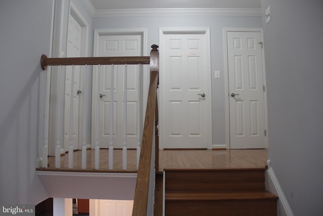 staircase with crown molding, baseboards, and wood finished floors