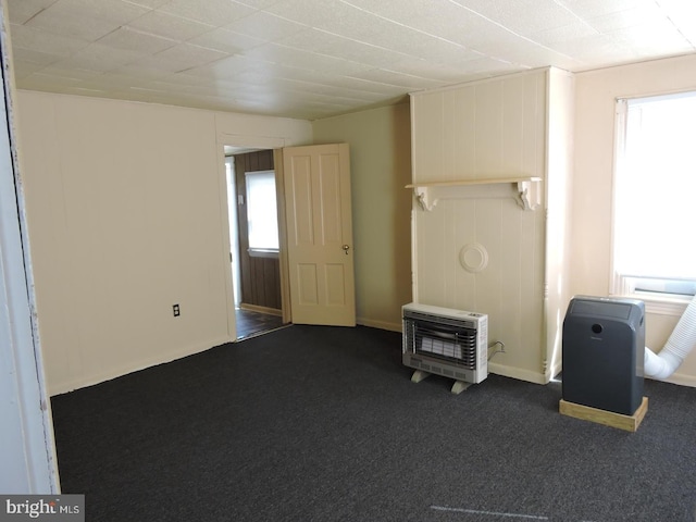 interior space with dark carpet, heating unit, and plenty of natural light