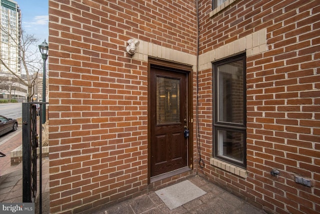 view of exterior entry featuring brick siding