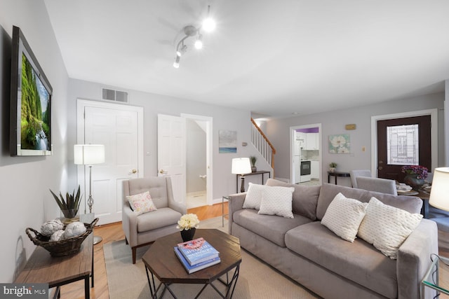 living area featuring stairs, light wood-style flooring, and visible vents