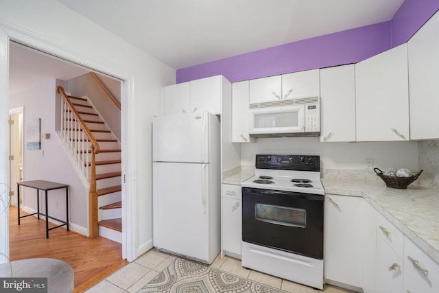 kitchen with light tile patterned floors, light countertops, white cabinetry, white appliances, and baseboards