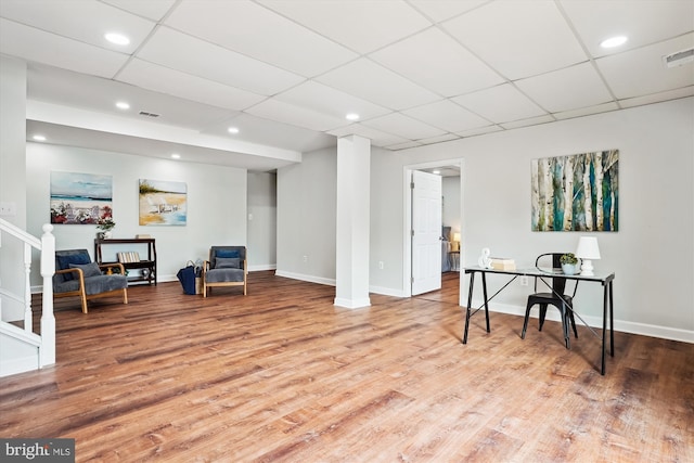 living area featuring wood-type flooring and a paneled ceiling