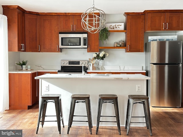 kitchen featuring a breakfast bar, an inviting chandelier, hanging light fixtures, stainless steel appliances, and light hardwood / wood-style flooring