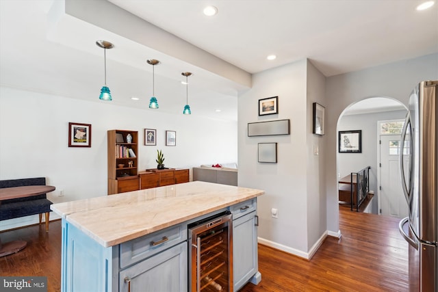 kitchen with arched walkways, wine cooler, dark wood-type flooring, freestanding refrigerator, and pendant lighting