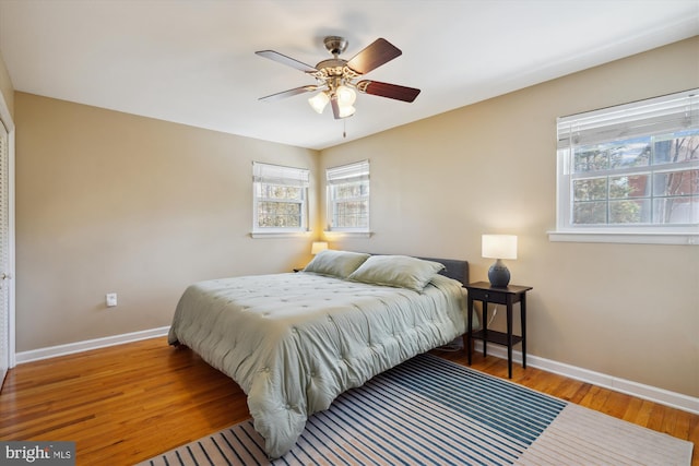 bedroom with ceiling fan, wood finished floors, and baseboards