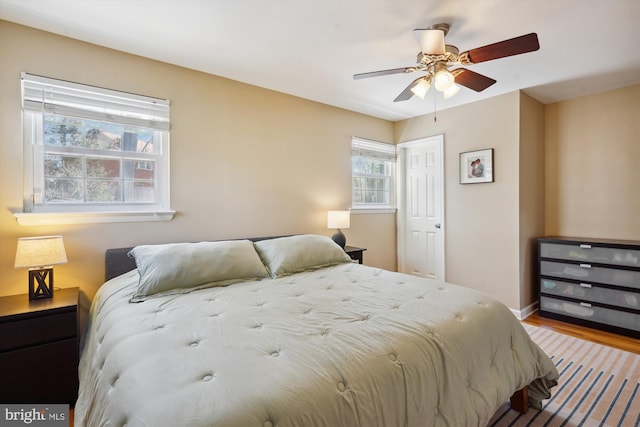 bedroom with a ceiling fan, baseboards, and wood finished floors