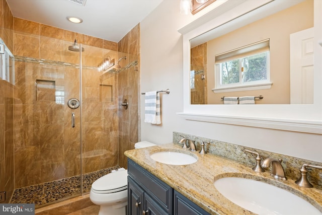 full bath featuring toilet, a shower stall, double vanity, and a sink