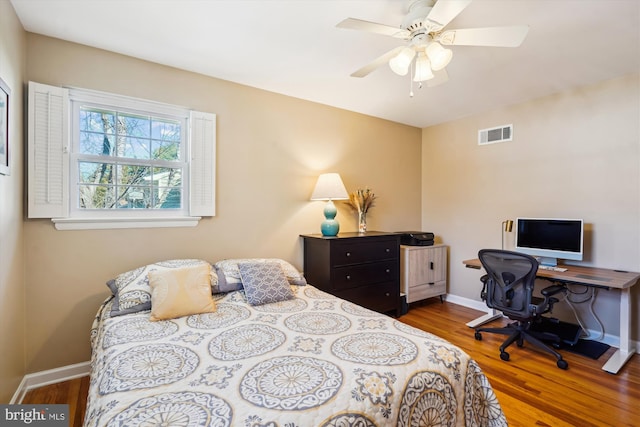 bedroom with ceiling fan, wood finished floors, visible vents, and baseboards