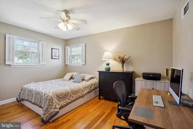 bedroom featuring baseboards, a ceiling fan, visible vents, and light wood-style floors