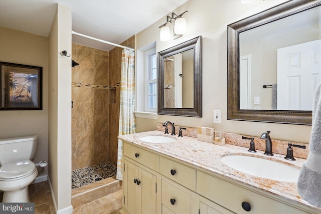 full bathroom featuring double vanity, tiled shower, a sink, and toilet