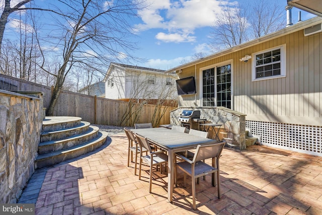 view of patio with outdoor dining space, a grill, and fence