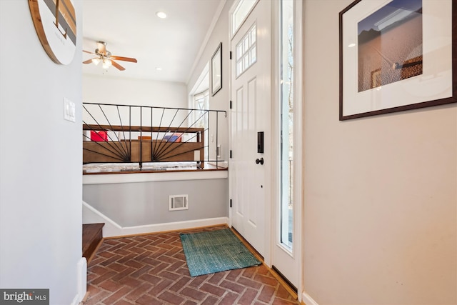 entrance foyer with stairway, brick floor, visible vents, and baseboards