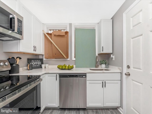 kitchen with white cabinetry, appliances with stainless steel finishes, sink, and light stone counters