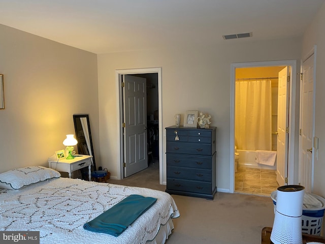 bedroom with a walk in closet, carpet flooring, and ensuite bath
