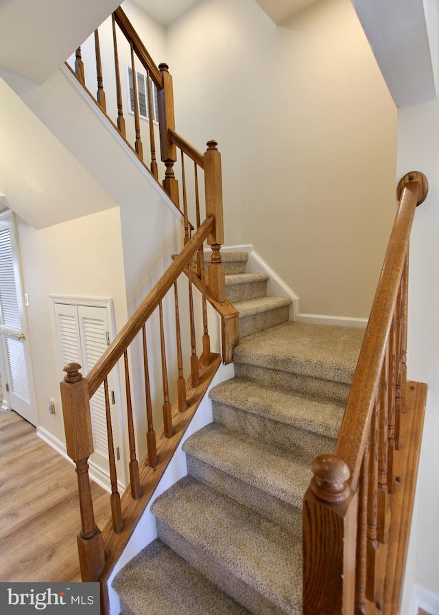 stairs with baseboards, a towering ceiling, and wood finished floors