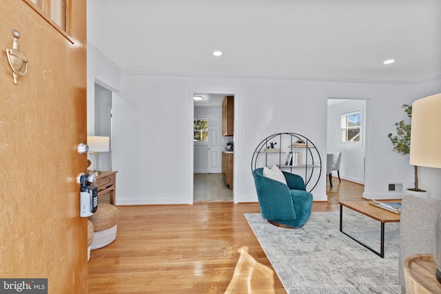 sitting room with ornamental molding and light wood-type flooring