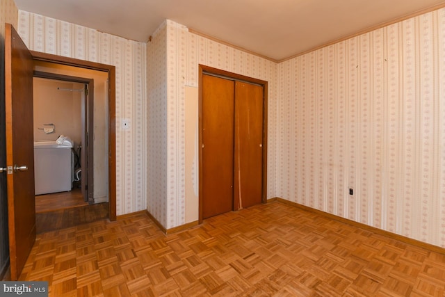 unfurnished bedroom with washer / clothes dryer, light parquet flooring, crown molding, and a closet