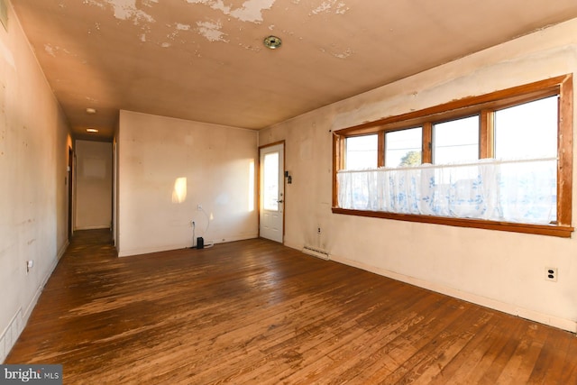 unfurnished room with dark hardwood / wood-style floors and baseboard heating