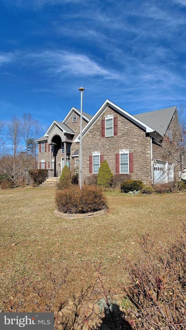 view of front facade with stone siding and a front lawn