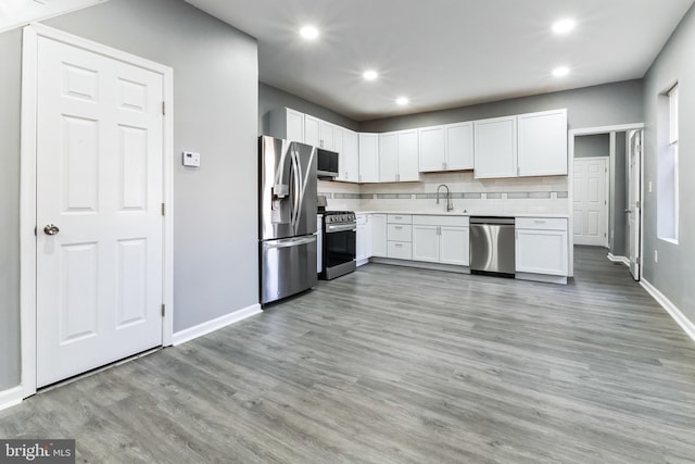 kitchen featuring a sink, light countertops, appliances with stainless steel finishes, light wood finished floors, and tasteful backsplash