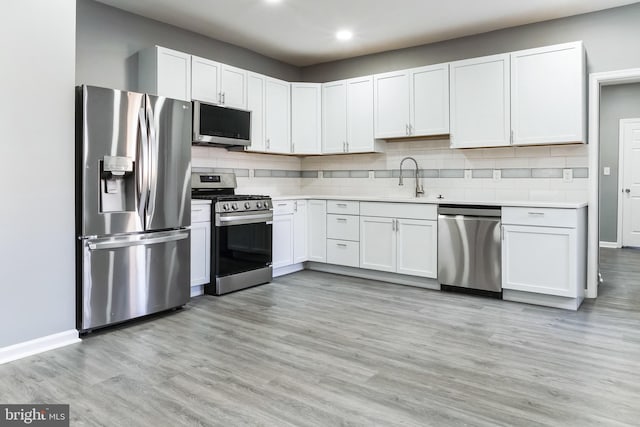 kitchen with backsplash, stainless steel appliances, a sink, and light countertops