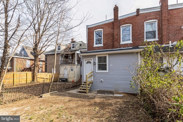 rear view of property with entry steps and fence