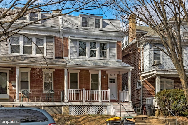 view of property with covered porch and brick siding